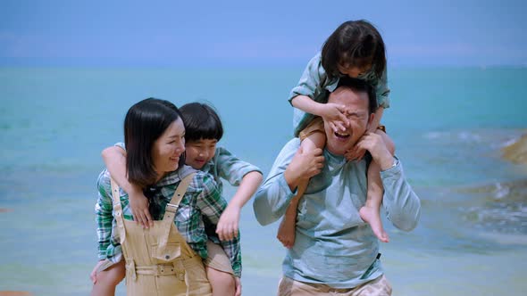 Asian families are happily teasing on the beach on vacation of relaxation