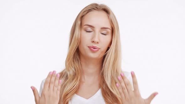 Young Beautiful Caucasian Blonde Girl Waving Hands From Imaginary Heat on White Background in alt