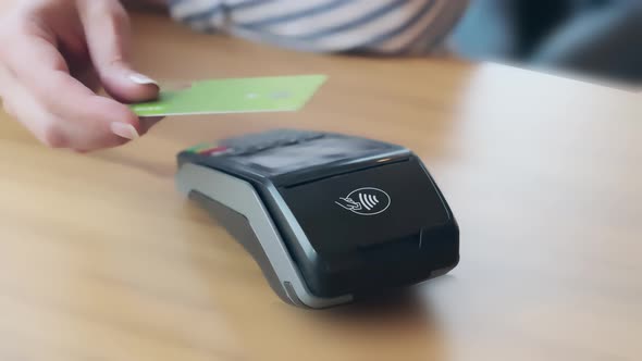 The customer uses a credit card to pay the owner in a cafe-restaurant, cashless technology.