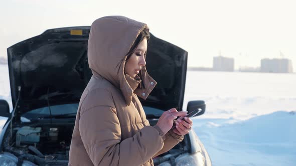 Woman with Phone Waits for Tow Truck Near Broken Car alt