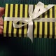 Girl  hand holding a gift wrapped in striped black yellow paper tied with white ribbon - VideoHive Item for Sale