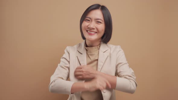 Happy asian business woman standing and laughing standing isolated over beige background. 4K video