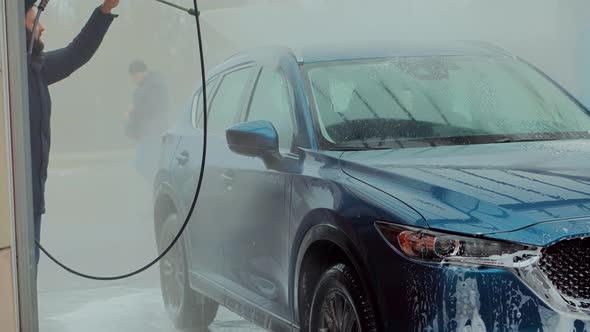 Man Washing Car On Wash Self-Service.Washes Automobile with Foam And Osmosis Water. alt