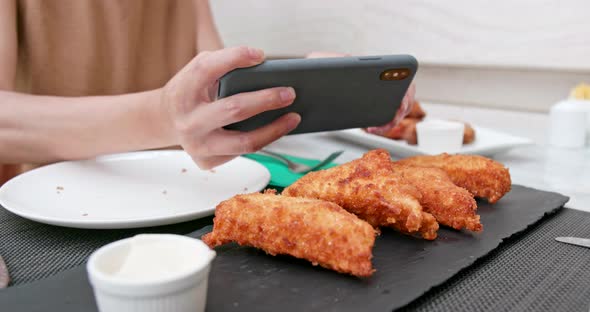 Woman Taking Photo on Her Fried Chicken Wing alt