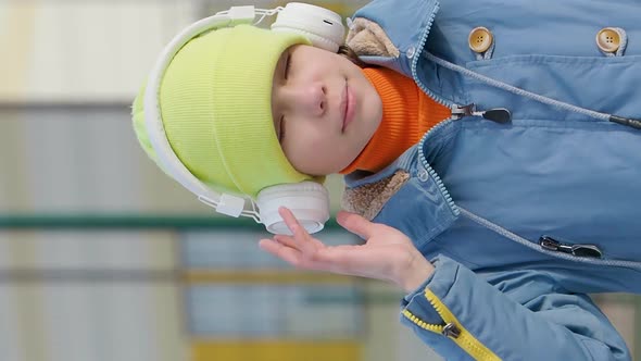 Vertical Video of a Teenager Girl Listening to the Music Via Wireless Headphones and Online alt