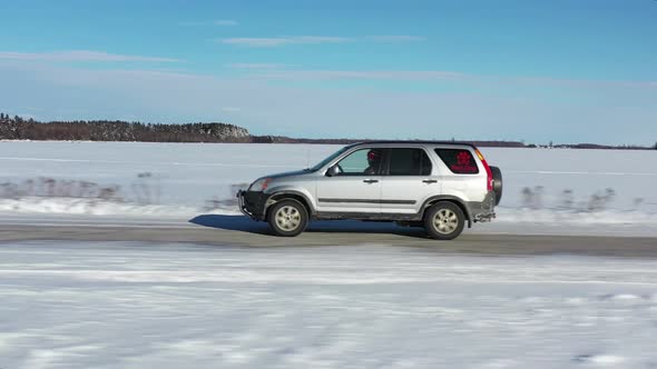 suv driving in remote winter area on snowy road close up aerial alt