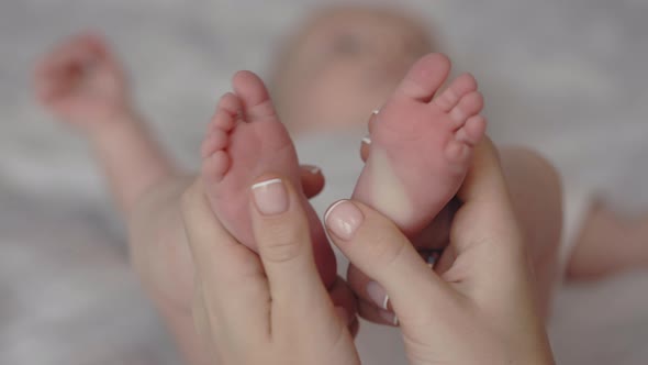Close Up of Mother Touching Gently Bare Feet of Newborn Son