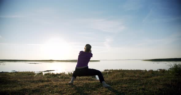 Silhouette of Young Sporty Woman Engaged in Gymnastics on Background Sky and Lake. V4 alt
