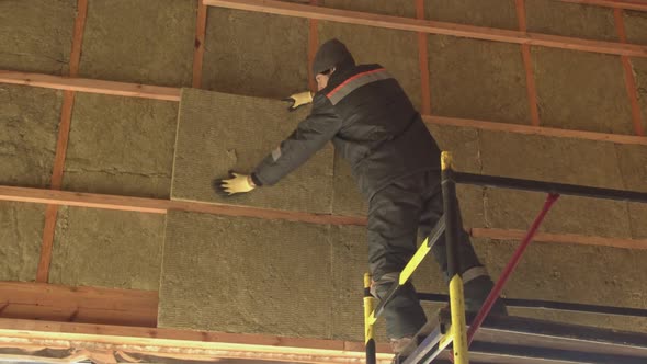 Man laying insulation at height