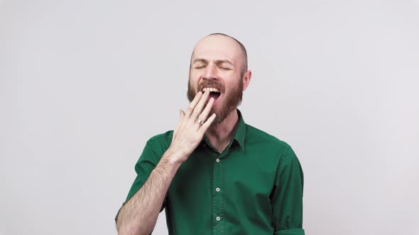 Portrait of a sleepy man yawning or feeling boredom isolated over white background.