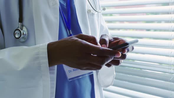 Mid section of African American male doctor using mobile phone in hospital 4k alt
