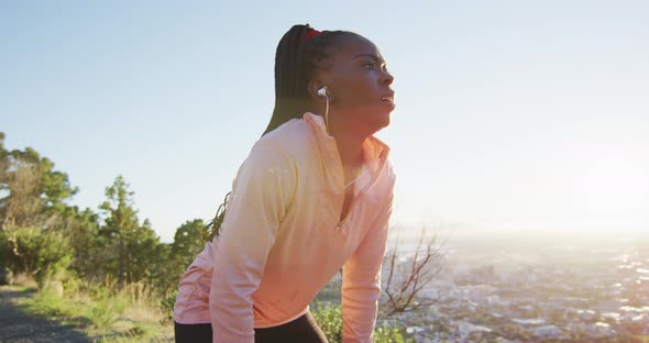 African american woman exercising outdoors wearing earphones preparing to run in countryside alt