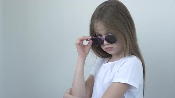 Cool Confident Little Girl with Takes Off Her Glasses and Looking at Camera alt