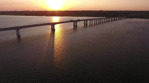 Aerial Shot of a Beautiful River Bridge Over the Dnipro with a Golden Sun Path
