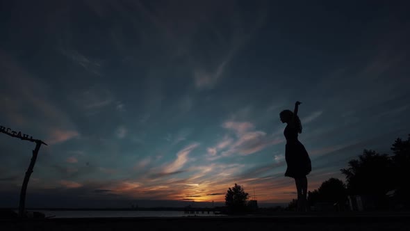 Ballerina Makes High Beautiful Jumps. Silhouette of a Ballerina Against the Sunset Sky