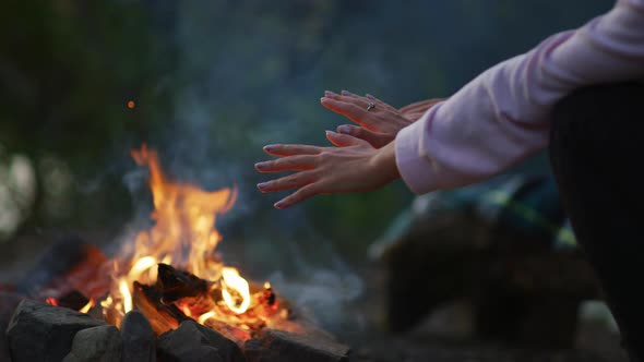 Hands warming at a campfire alt