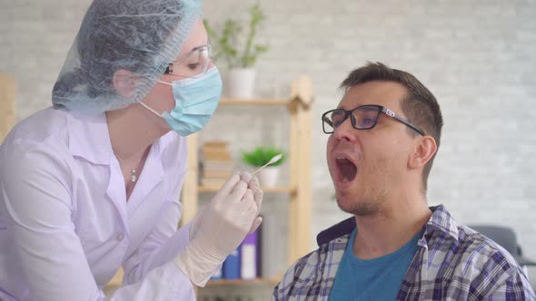 Woman Lab Technician Taking a Saliva Test From a Man's Mouth with a Cotton Swab alt