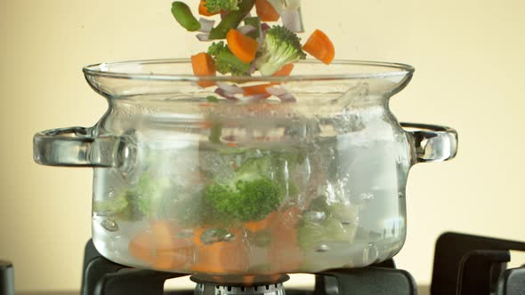 Super Slow Motion Shot of Fresh Vegetable Falling Into Boiling Salted Water at 1000 Fps. alt