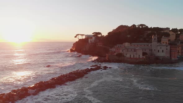 Aerial of Baia del silenzio, Sestri Levante, Italy. Ancient church by the sea at sunset. The waves h alt