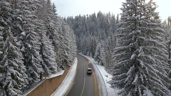 Aerial View of Winter Landscape with Snow Covered Mountain Woods and Winding Forest Slippery Road alt
