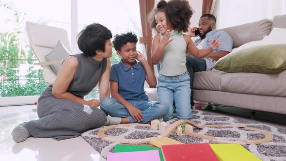 Love moment of African American little son, daughter and mom enjoy toy cars on floor in living room