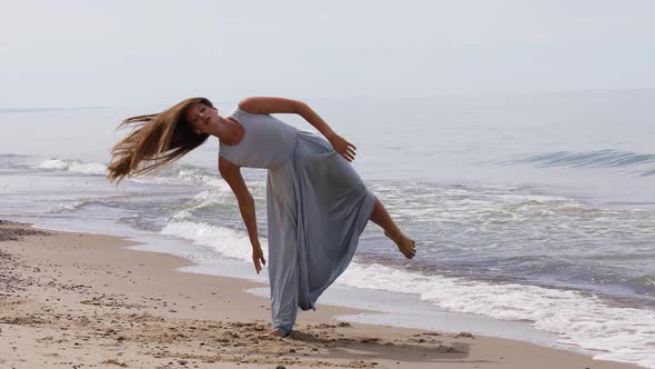Nice Young Woman in a Long Dress Dancing on The Beach 