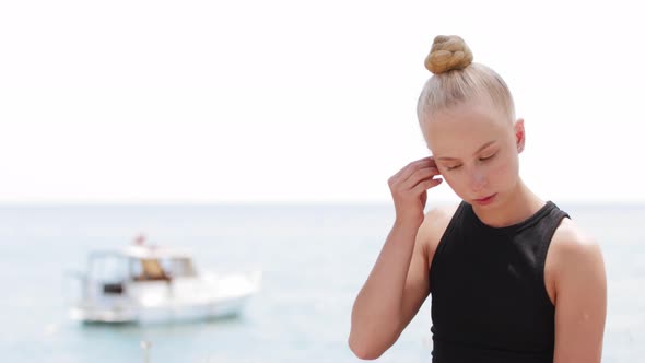 Young Blonde Woman Puts in Wireless Headphones alt