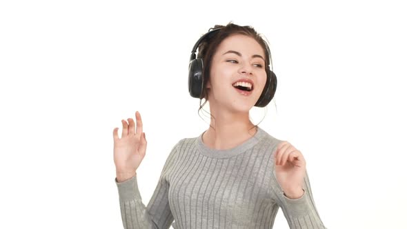 Joyful Smiling Caucasian Brunette Girl Dancing on White Background Listening Music Through Black alt