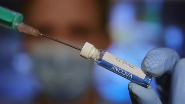 Closeup of a medical with face mask filling syringe with a covid-19 vaccine.