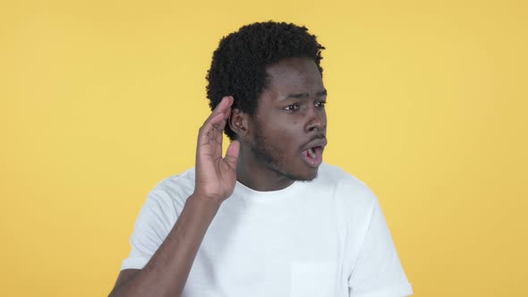 African Man Listening Secret Yellow Background alt