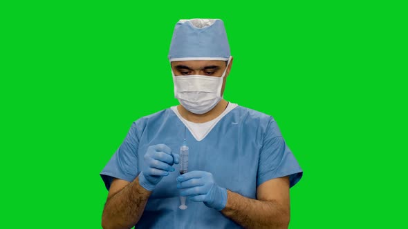 Asian Medic In Mask And Uniform Preparing Syringe For Injection on Green Screen