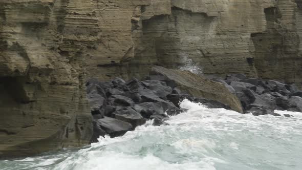 Powerful waves hitting rocky cliffs and falling to produce froth and splashes alt