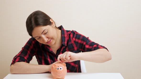 Sly Young Woman Pulls Dollar Banknote Out of Piggy Bank Slot alt