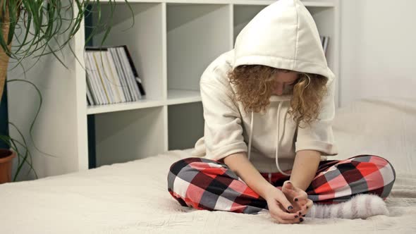 Teenage Girl Sits Alone on the Bed and Cries Covering Her Face with Her Hands