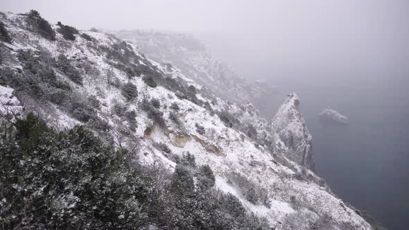 Snow Covered Rocky Cliffs Over Sea alt