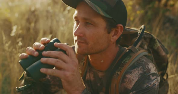 Bowhunter takes a closer look through his binoculars alt