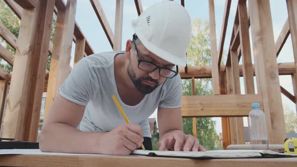 Builder-engineer Makes Notes in the Log of Work at Construction Site