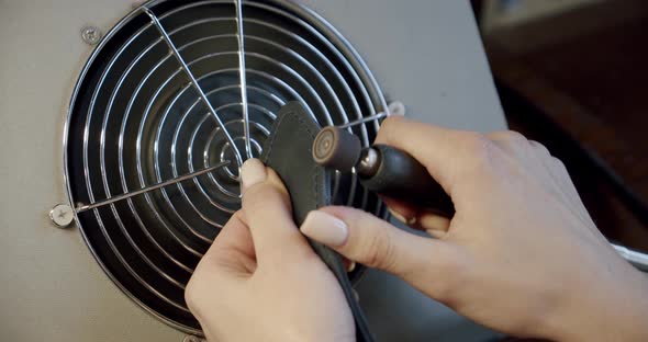 Young Woman Worker Burnishing Edge of a Leather Belt During Manufacturing Process in His Workshop alt