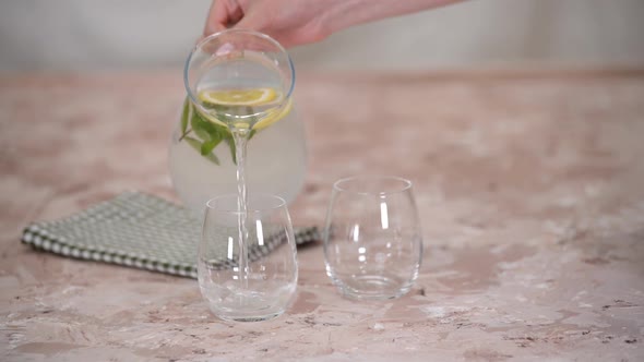 Closeup of Woman in Kitchen at Home Pouring Lemonade Into Glasses