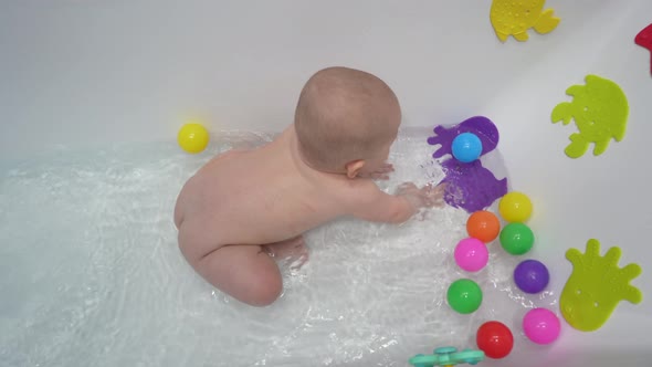 Cute Little Boy Taking a Bath with Toys in a White Bathroom