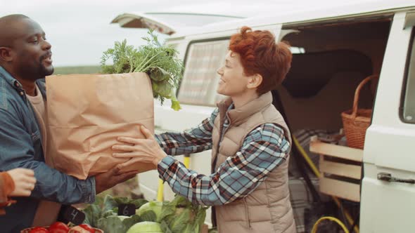 Cheerful Female Farmer Selling Fresh Vegetables to Multiethnic Customers alt