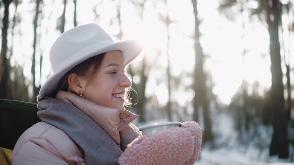 Beautiful Woman Drinks Hot Drink in the Woods in Winter Enjoying Camp Life