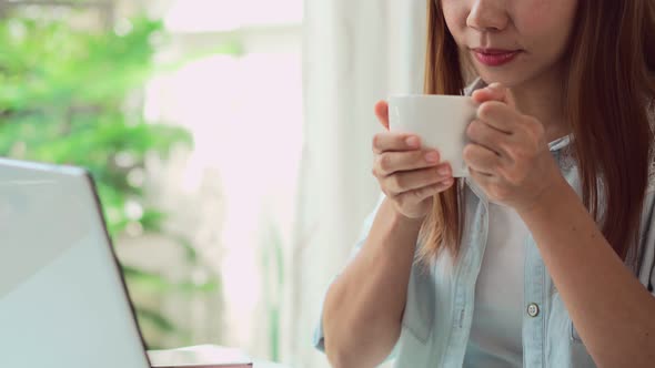 Young woman taking a coffee break and relaxing at living room while working at home