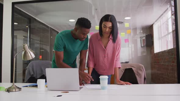 Diverse male and female business colleagues in discussion in meeting room analyzing documents alt