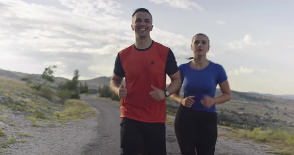 Tracking Slow Motion Shot of Sportive Couple Jogging Outdoors in the Morning Trail Running alt