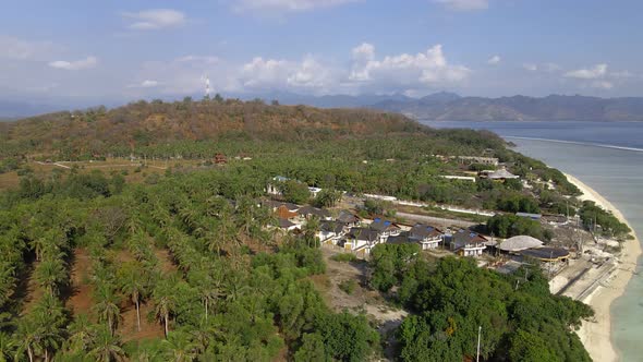 Aerial wide shot of green hills on Gili Trawangan Island with beach and ocean during sunlight. alt