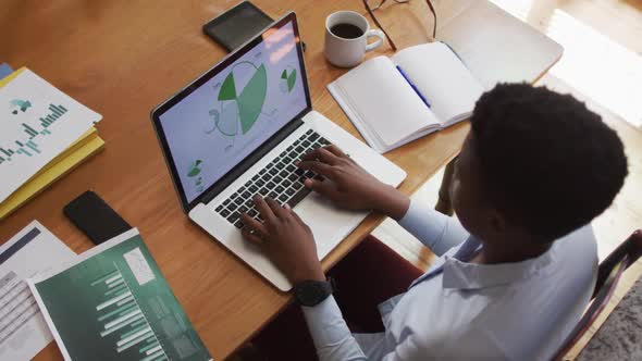 Overhead view of african american woman using laptop while working from home alt