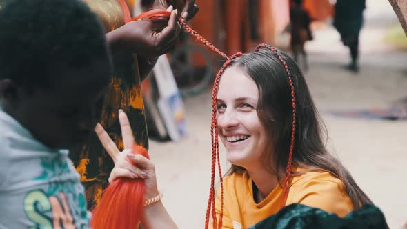 Process of Weaving African Braids with Red Kanekalon Outdoor Zanzibar Africa alt
