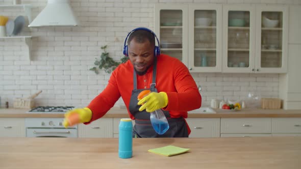 Positive African Man in Headphones Housekeeping in Kitchen alt