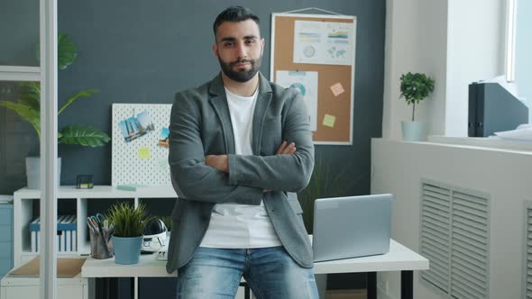 Slow Motion Portrait of Goodlooking Office Worker Standing Indoor with Arms Crossed alt